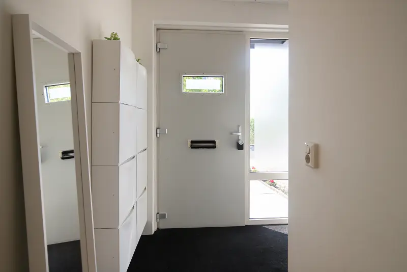 Hal bij de voordeur met witte inbouwkast en donkere vloer