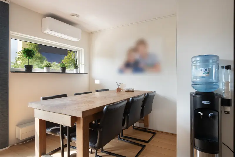 Lichte ruimte met airconditioning en lange tafel, geschikt als werk- of eetkamer