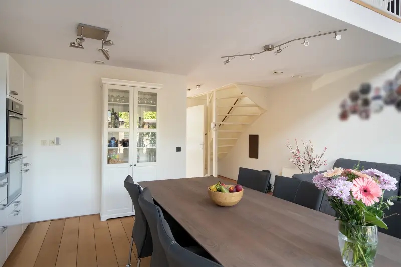Eethoek aan de keuken met houten eettafel en openslaande deuren naar buiten