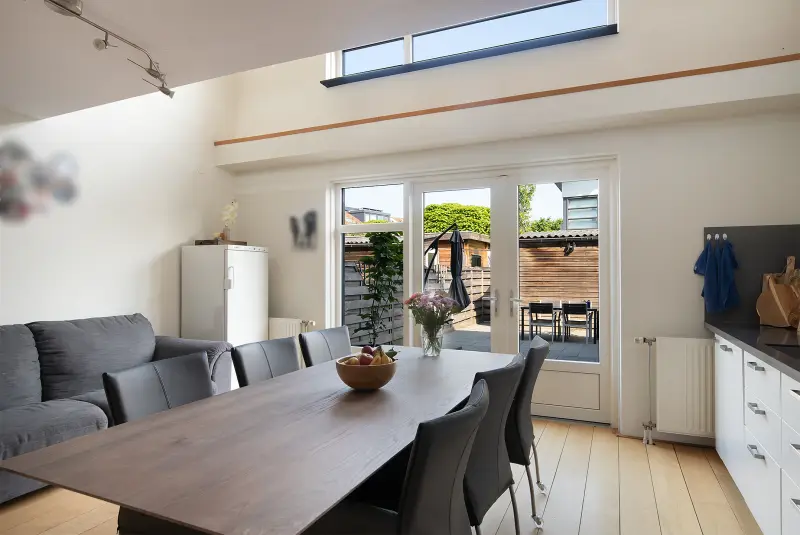 Eet- en zithoek aan de keuken met lichtkoepel en openslaande tuindeuren