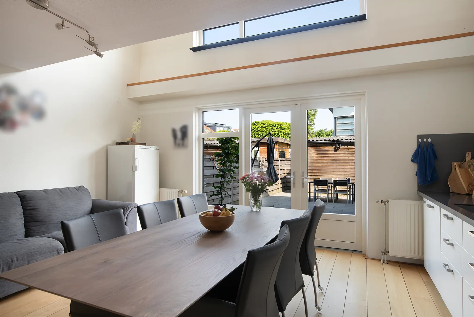 Lichte eet- en zithoek aan de keuken met lichtkoepel en openslaande deuren naar de tuin