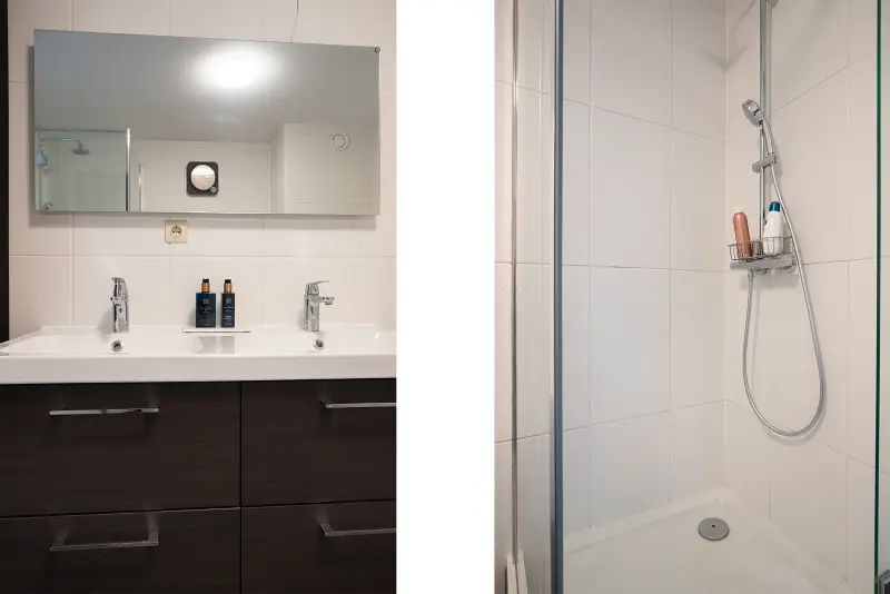 Badkamer met dubbele wastafel, grote spiegel en aparte inloopdouche