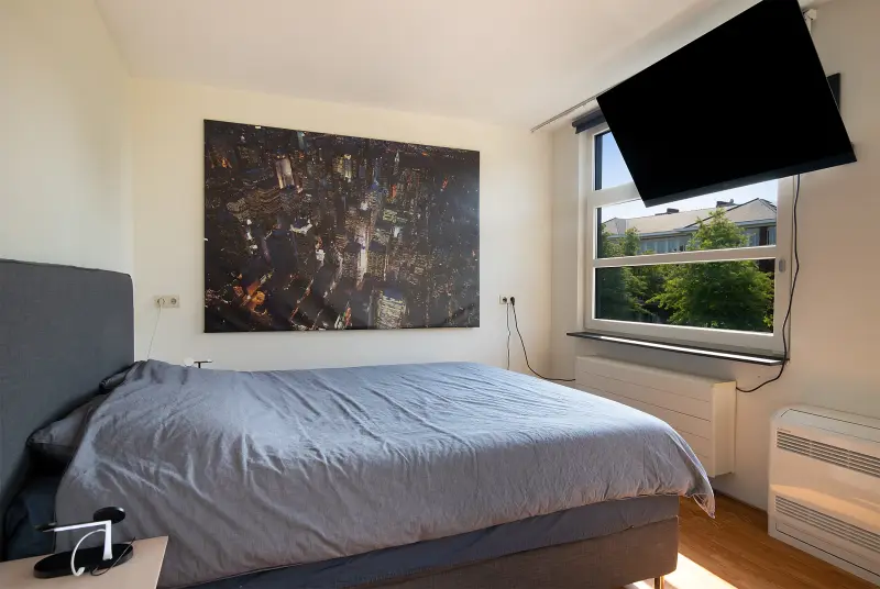 Master bedroom met tweepersoonsbed, kunst aan de wand en airconditioning