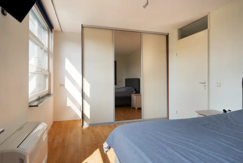 Slaapkamer met inbouwkast met spiegeldeuren en veel zoninval