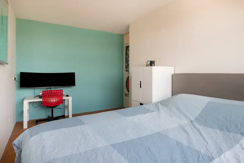 Slaapkamer met tweepersoonsbed en gedempt groene accentwand