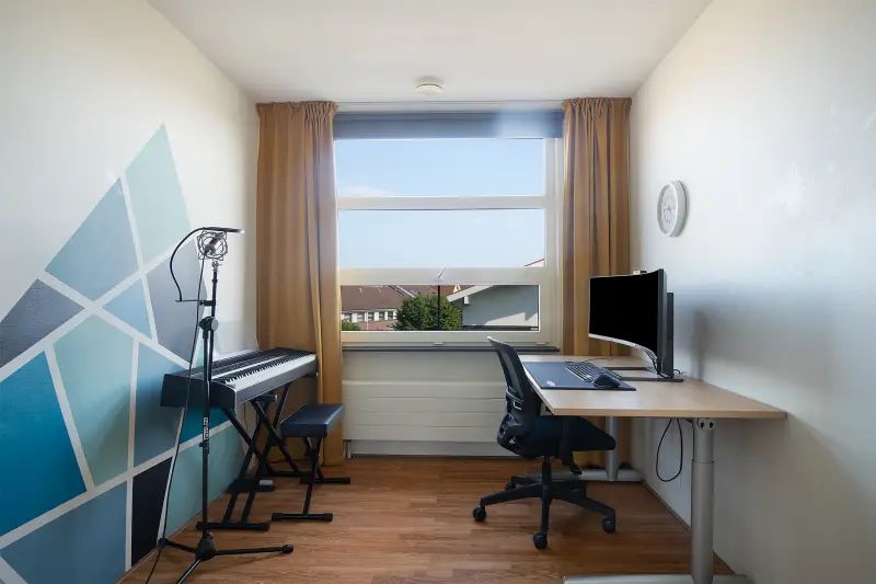 Flexibele kamer met bureau en piano, nu in gebruik als studeer- en muziekkamer