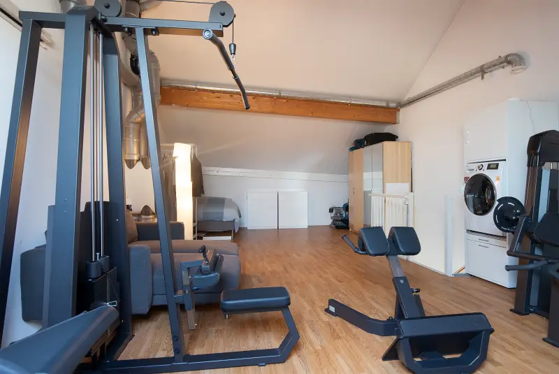 Zolder met opstelplek voor was- en droogapparatuur naast de fitnesshoek