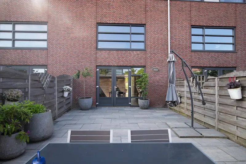 Achterzijde van de woning met bakstenen gevel en openslaande deuren naar de tuin