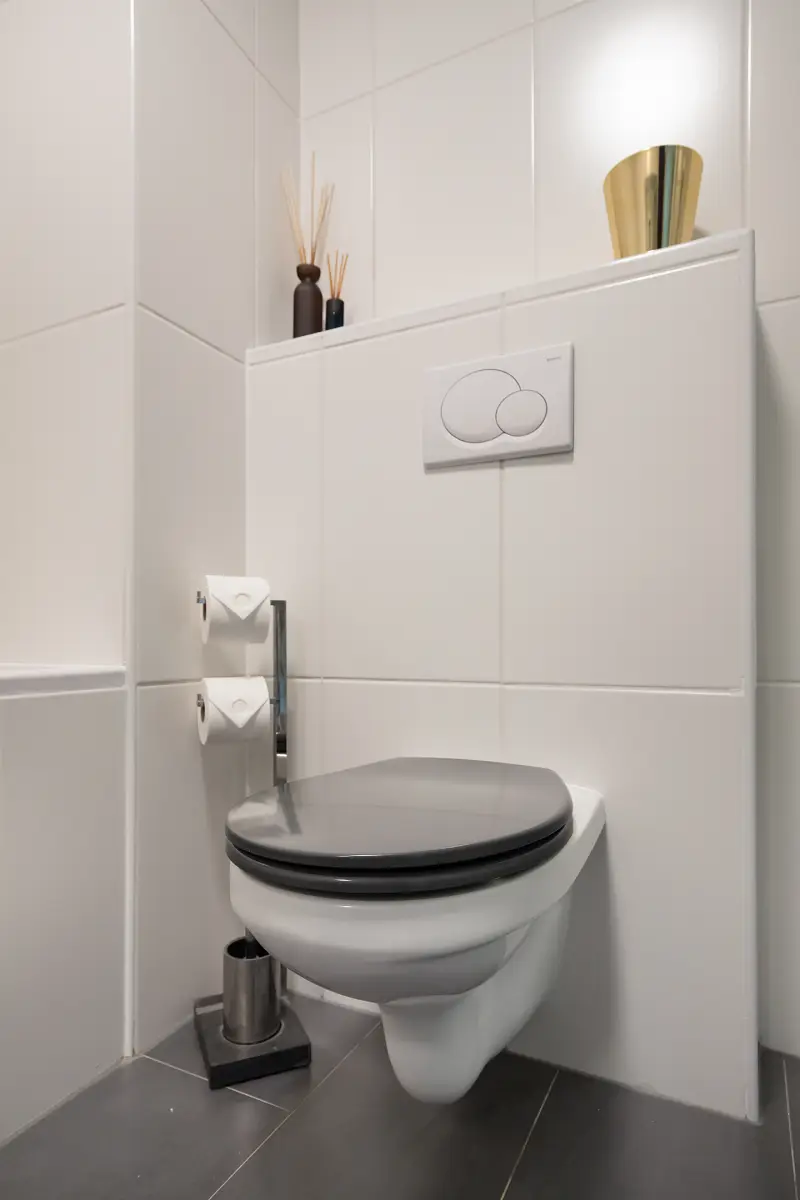 Modern toilet met wandcloset, lichte tegels en planchet